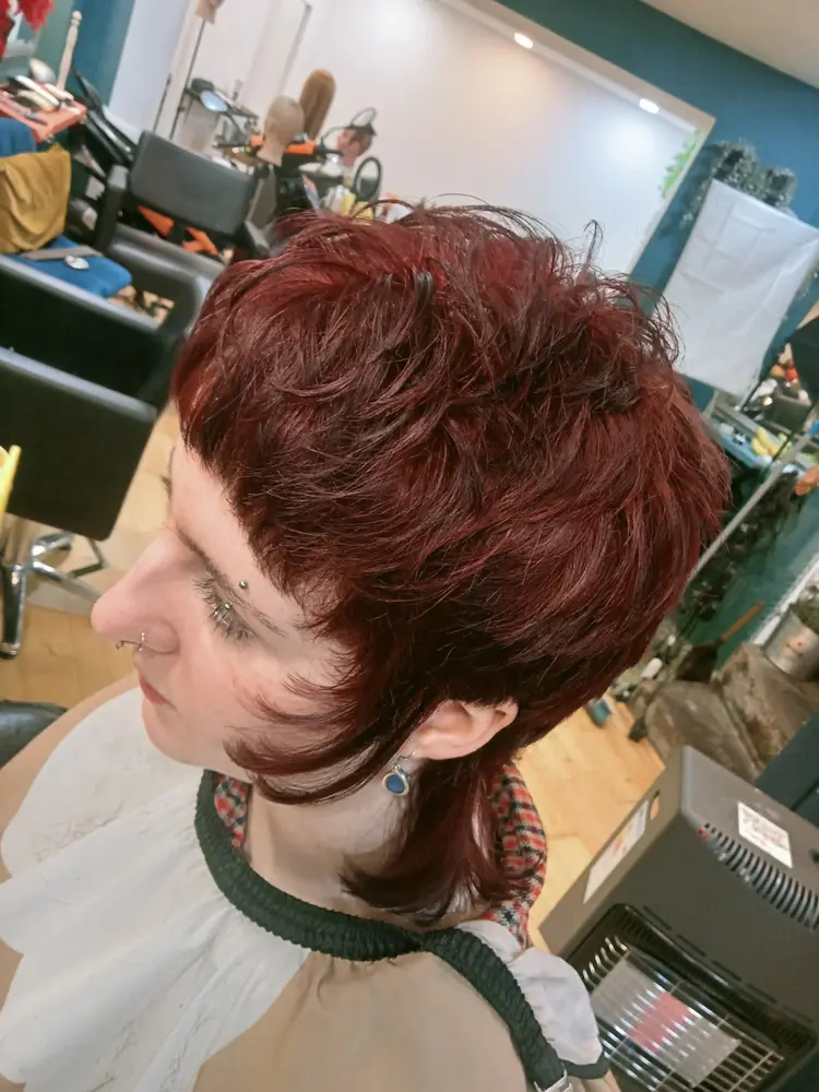 Finished red mullet haircut against the salon's teal wall